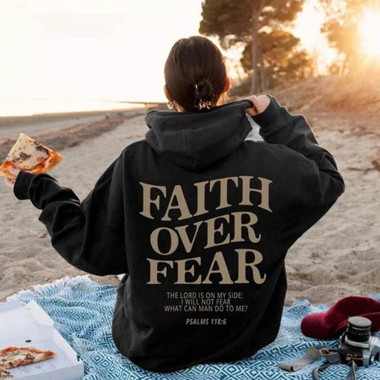Black Faith Over Fear hoodie with inspirational Psalm 118:6 text worn outdoors on a beach