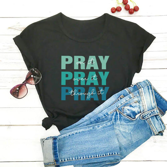 Black faith themed t shirt with Pray graphic text paired with blue jeans and sunglasses