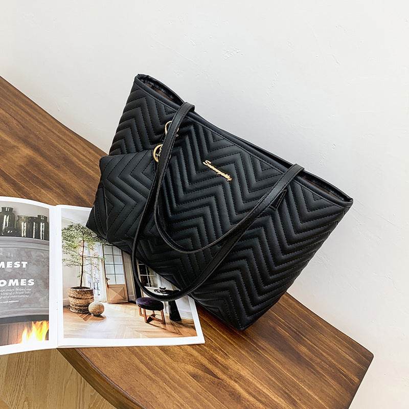 Holy Mango Store large quilted shoulder bag with zipper in black on wooden table with open magazine