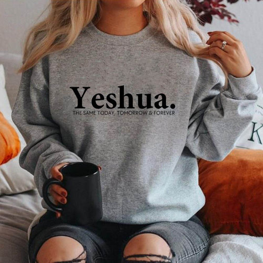 Woman wearing a gray vintage Yeshua sweatshirt with black text holding a black mug
