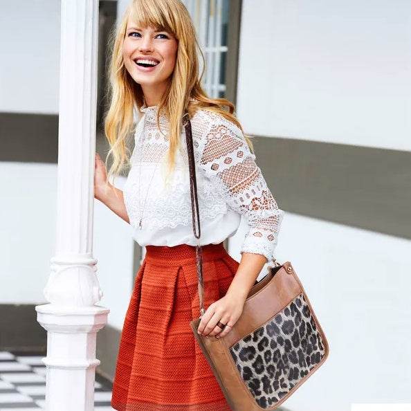 Holy Mango Store tan leather casual shoulder purse for women with leopard panel shown on smiling woman in lace top and red skirt
