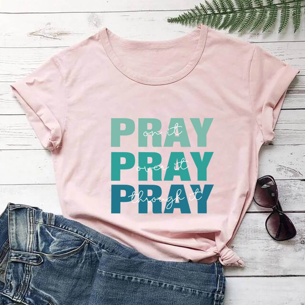 Pink faith themed t shirt with green and blue Pray text paired with denim shorts and sunglasses