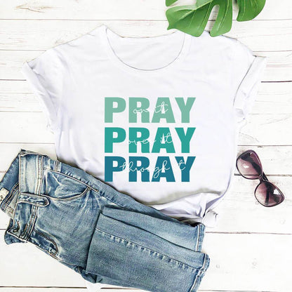 White faith themed t shirt with the word PRAY in blue and green shades from Holy Mango Store