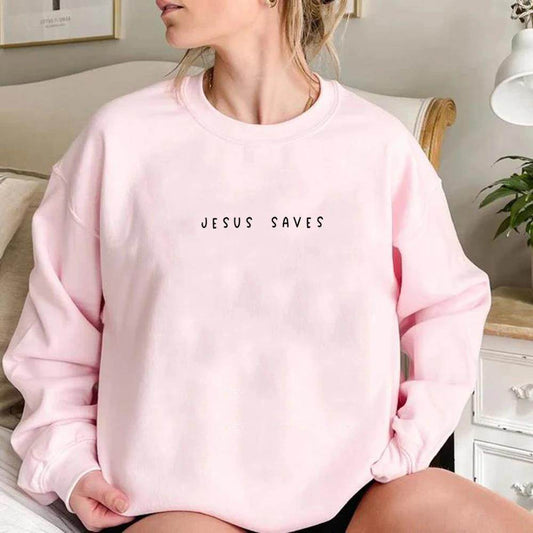 Light pink Jesus Saves sweatshirt with black text worn by woman sitting indoors