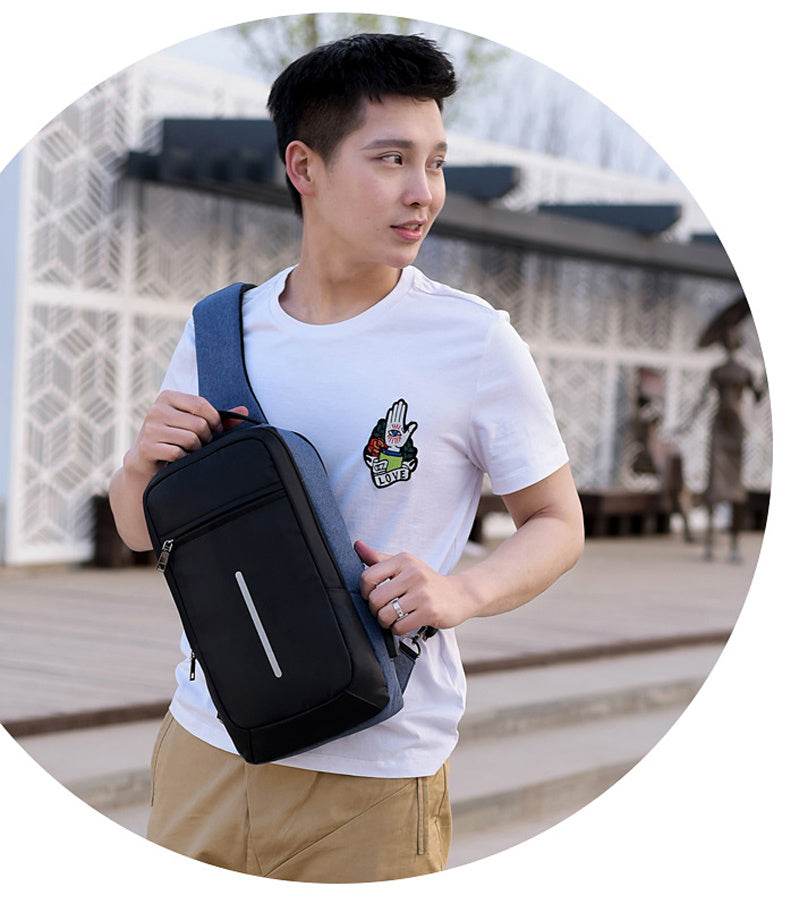 Holy Mango Store black anti-theft chest bag with USB charging worn crossbody by man in white tee outdoors