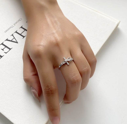 Close-up of a hand wearing a copper cross ring from Holy Mango Store on a white surface