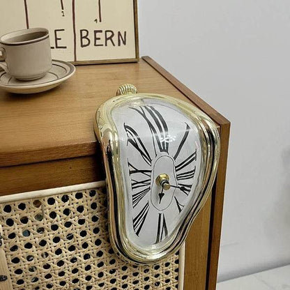 DALI inspired melting clock gold trim draped over mid century wooden cabinet edge with cup and framed print