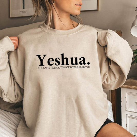 Woman wearing beige vintage Yeshua sweatshirt with black text from Holy Mango Store in cozy indoor setting